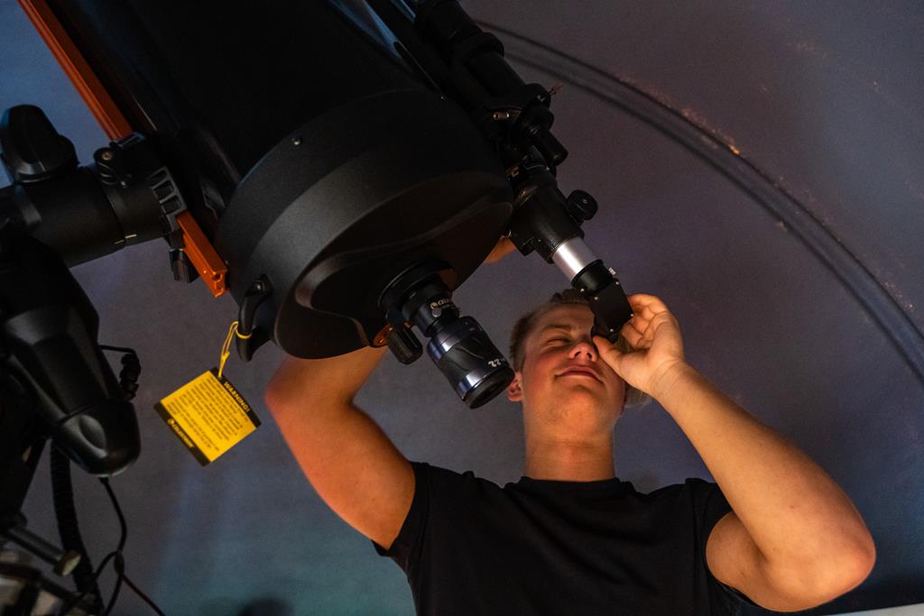 młody mężczyzna patrzy przez teleskop