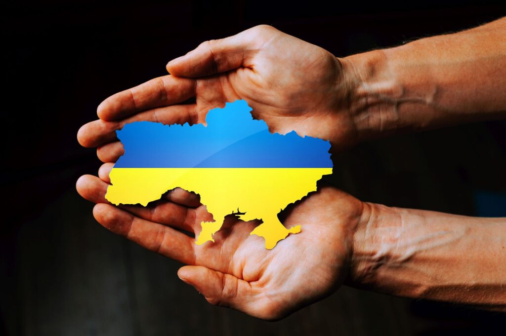 Ręce trzymające flagę Ukrainy w kształcie granic Ukrainy
