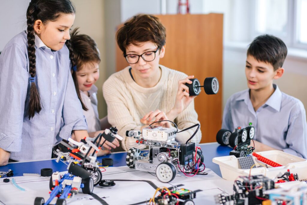 Uczniowie z nauczycielką uczą się programowania robota